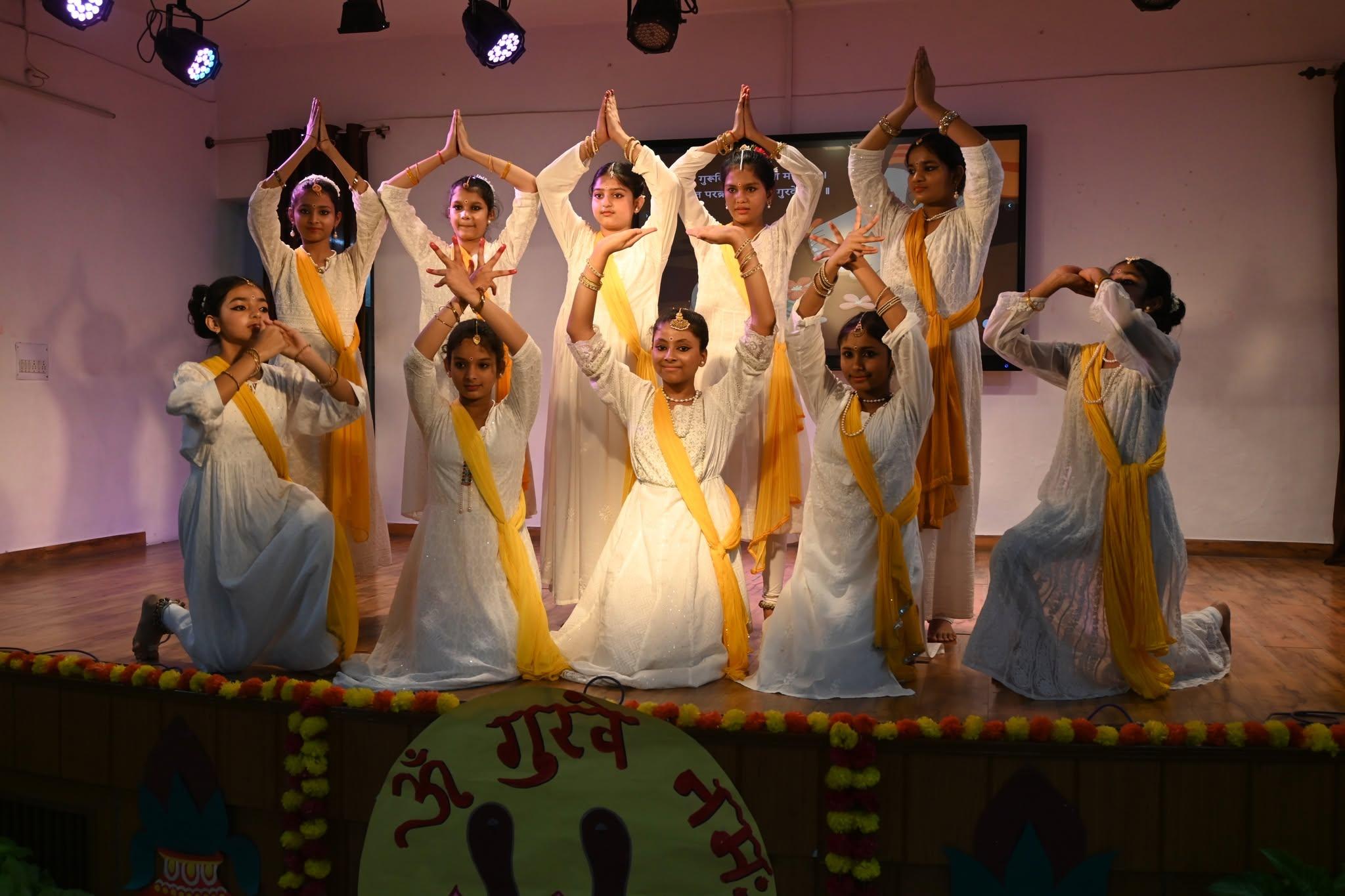 Dancers in costume performing under stage lights at Amritanjali